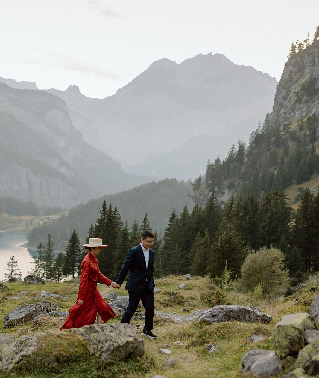 A couple photographed on a meadow with Swiss Alps and lake Oeschinensee in the background